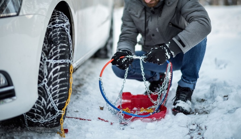 بستن زنجیر چرخ روی تایر خودرو در هوای برفی زمستان